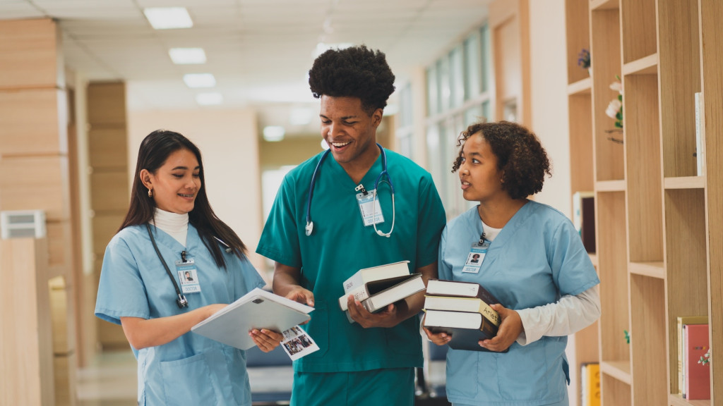 Three nursing students talking and carrying books